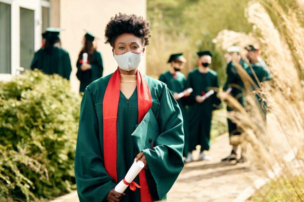 Portrait of happy African American female graduate with protective face mask.